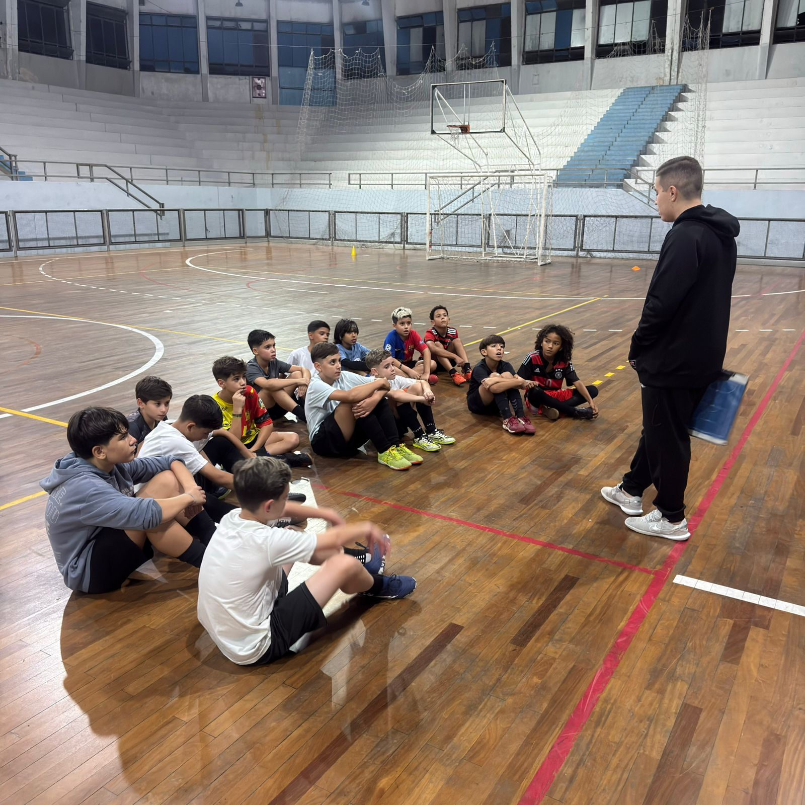 Crianças de 8 a 12 anos jogando futsal com coletes na quadra da FEG